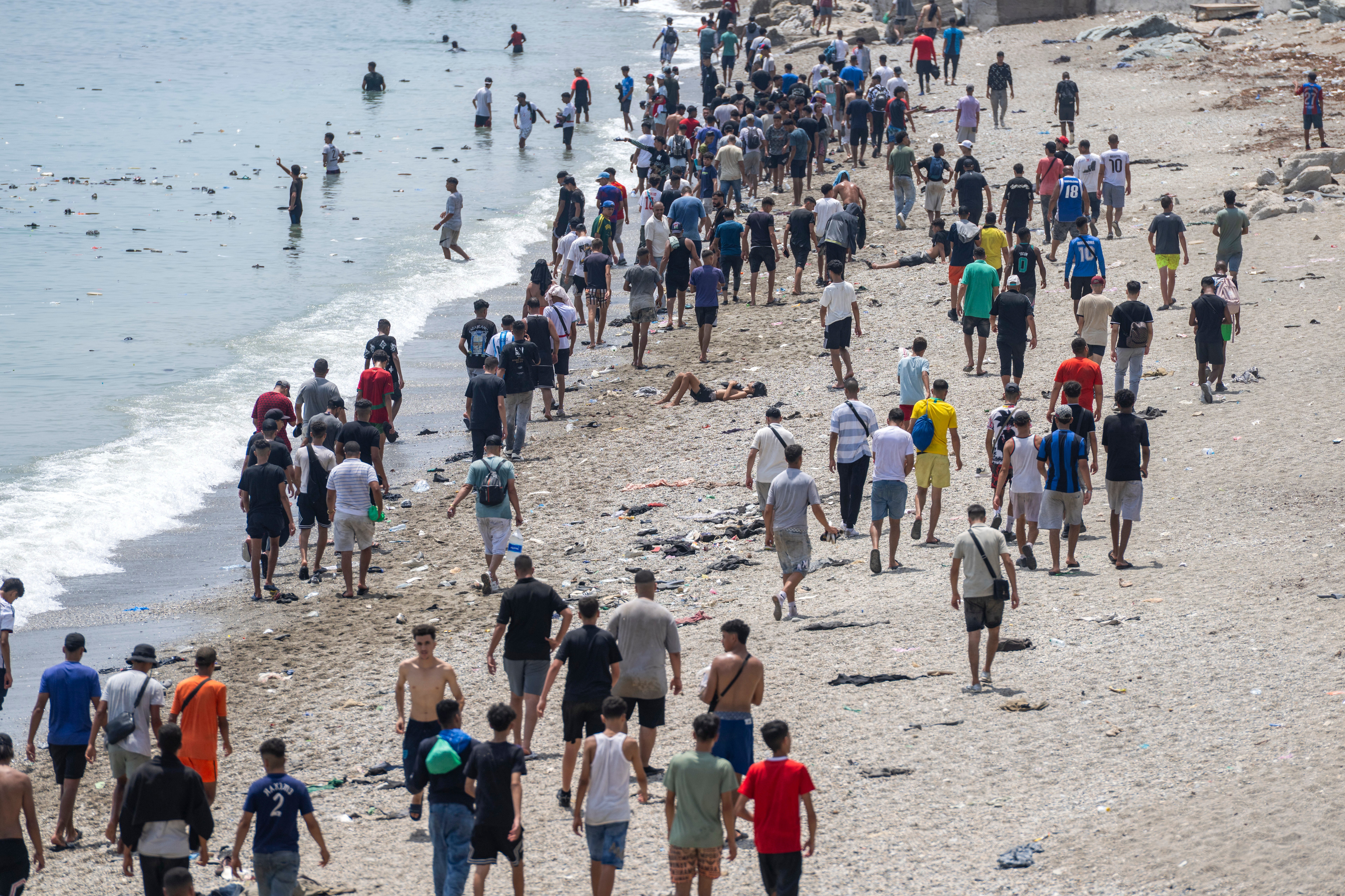 FILE - People walk on a beach after attempting to cross from the Moroccan northern town of Fnideq to the Spanish enclave of Ceuta, July 31, 2026. (AP Photo, File)