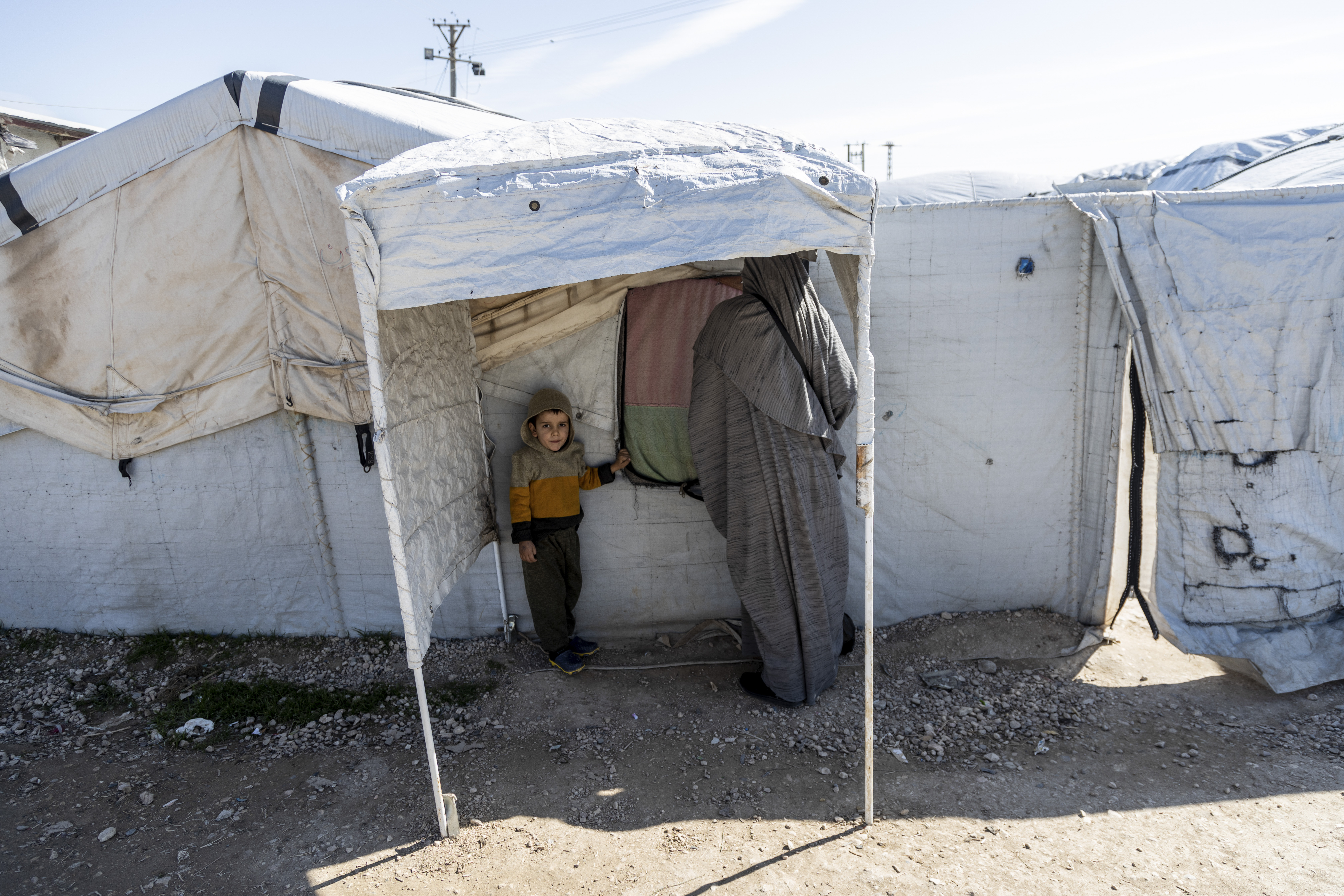 A woman and a child d stand in Roj detention camp in northeast Syria Wednesday, Feb. 9, 2022. Syrian Kurdish authorities are struggling to supervise tens of thousands of IS-affiliated foreign nationals they are holding in camps and prisons across northeast Syria, with no one to take them. A deadly prison attack last month has sharpened the focus on the detainees' uncertain future. (AP Photo/Baderkhan Ahmad)