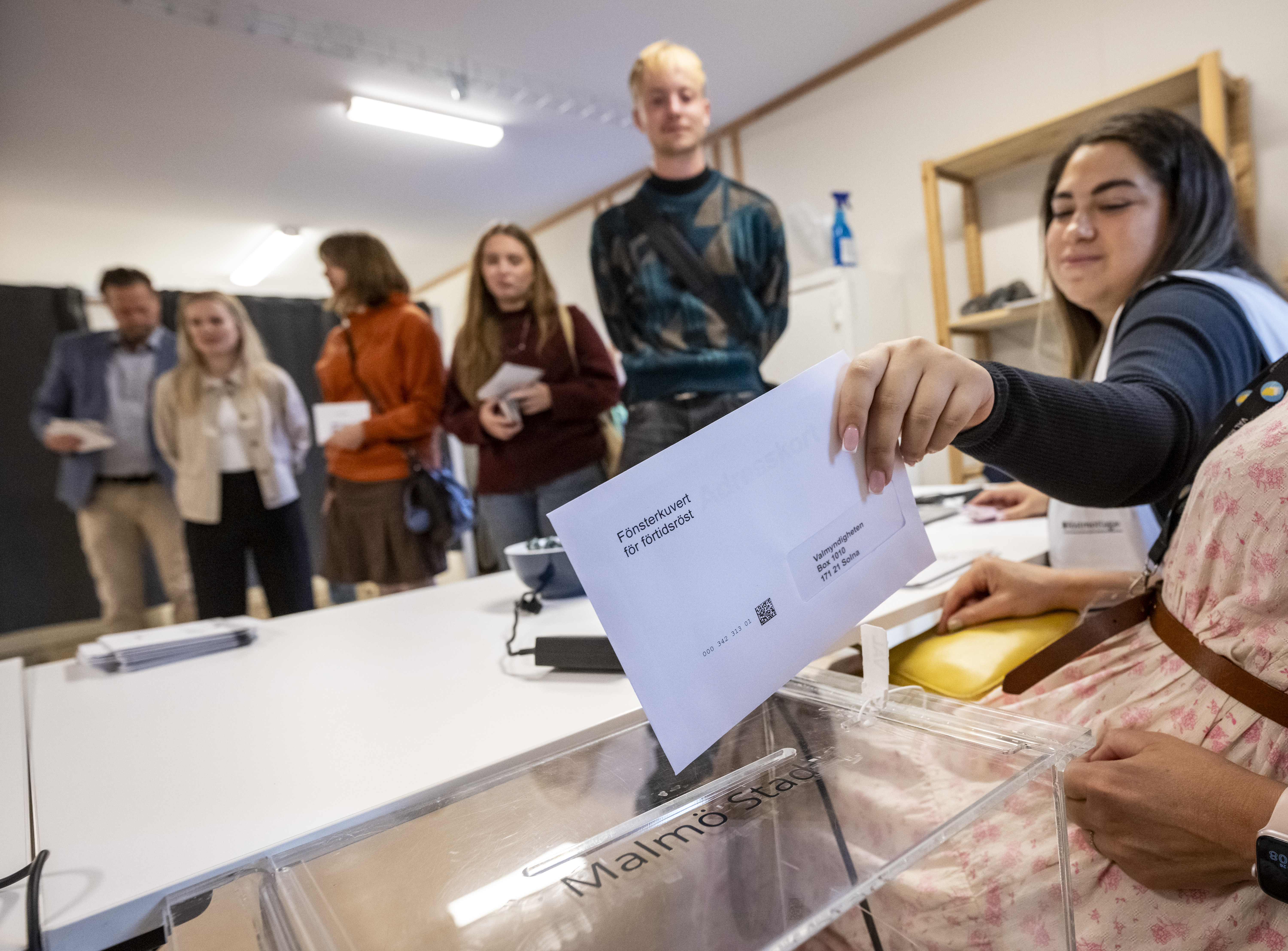 Ballot envelopes being placed into a ballot box at a polling station.