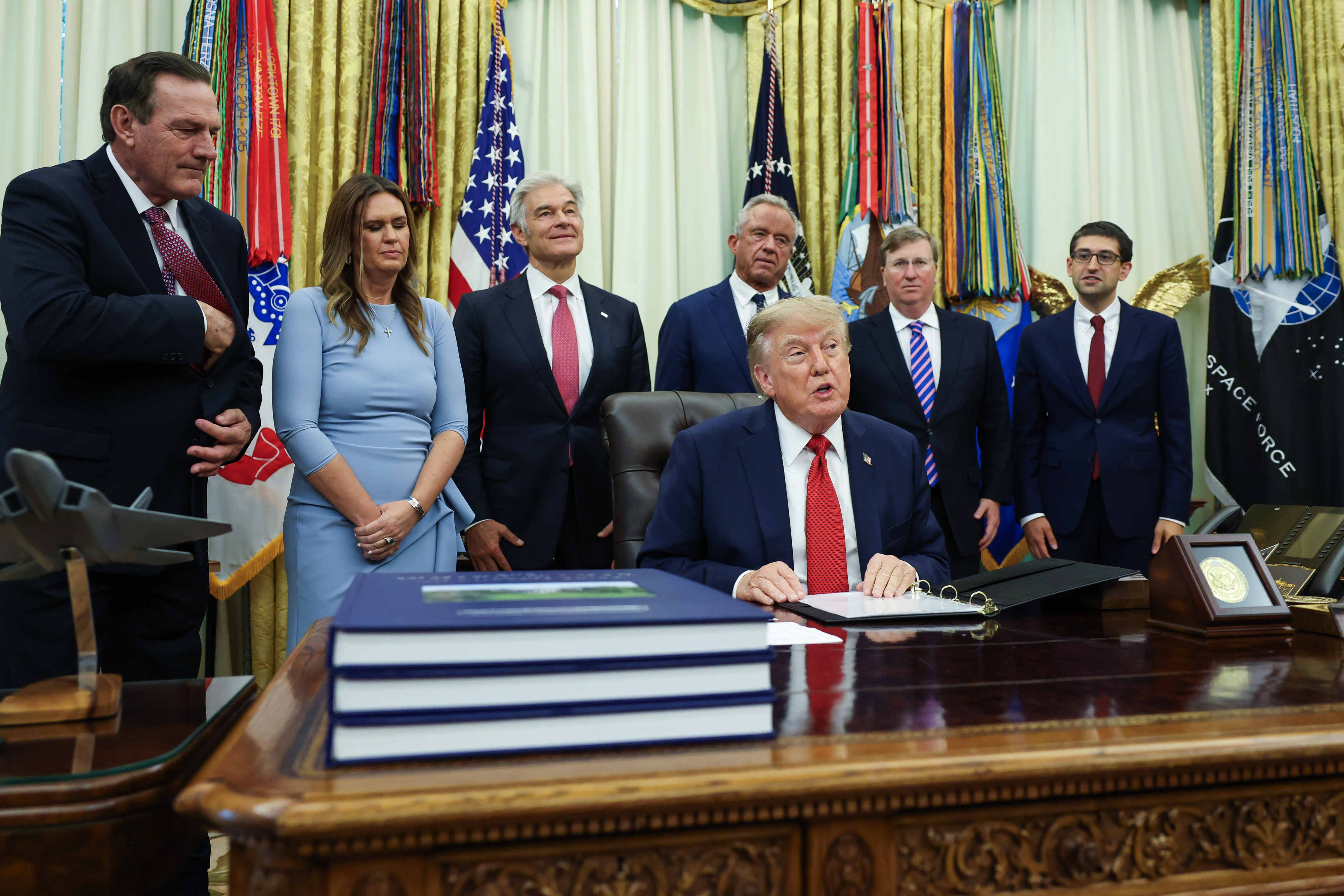 US President Donald Trump (C) with many people standing behind him in formal attire.