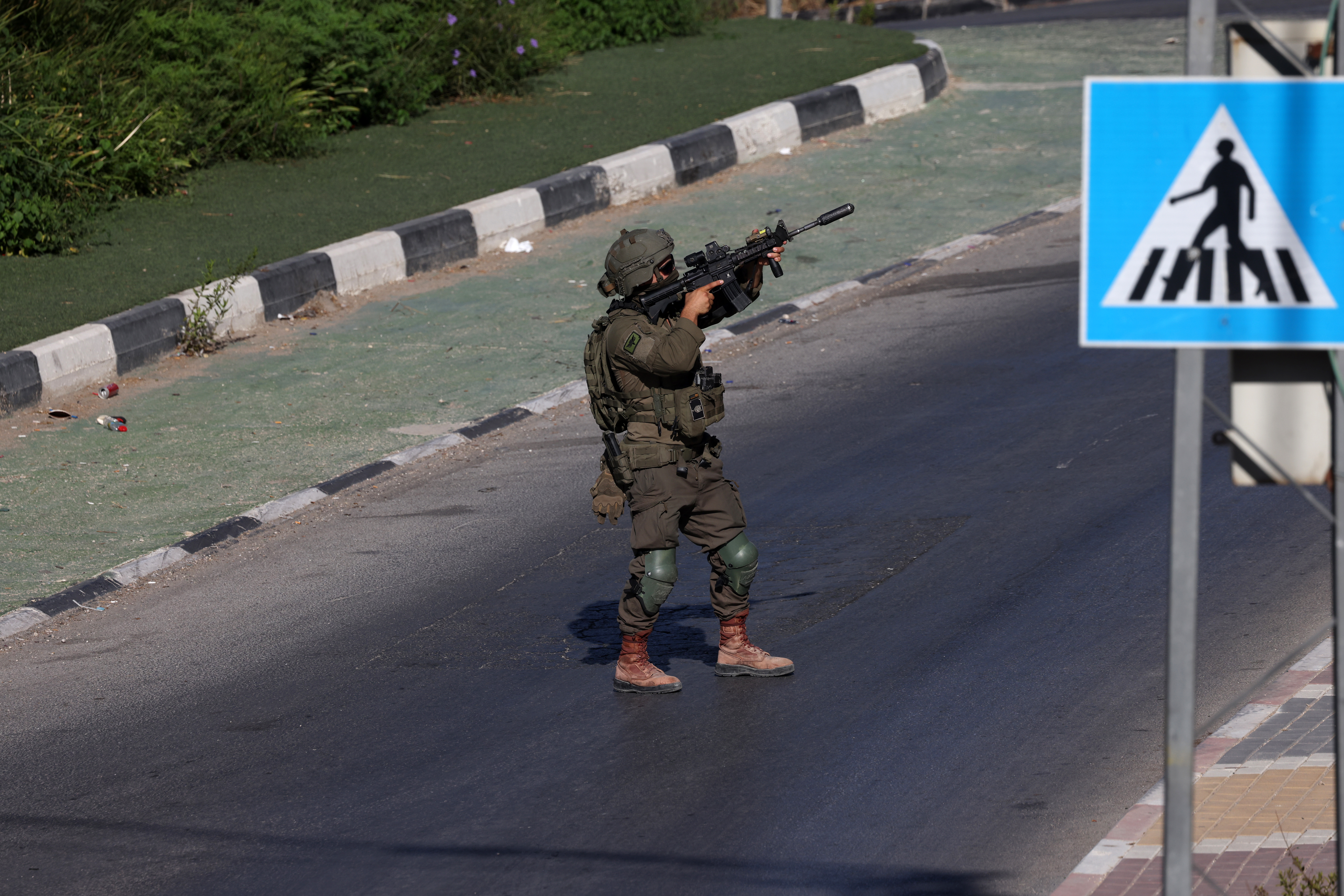 An Israeli soldier aims his gun on a dark street.