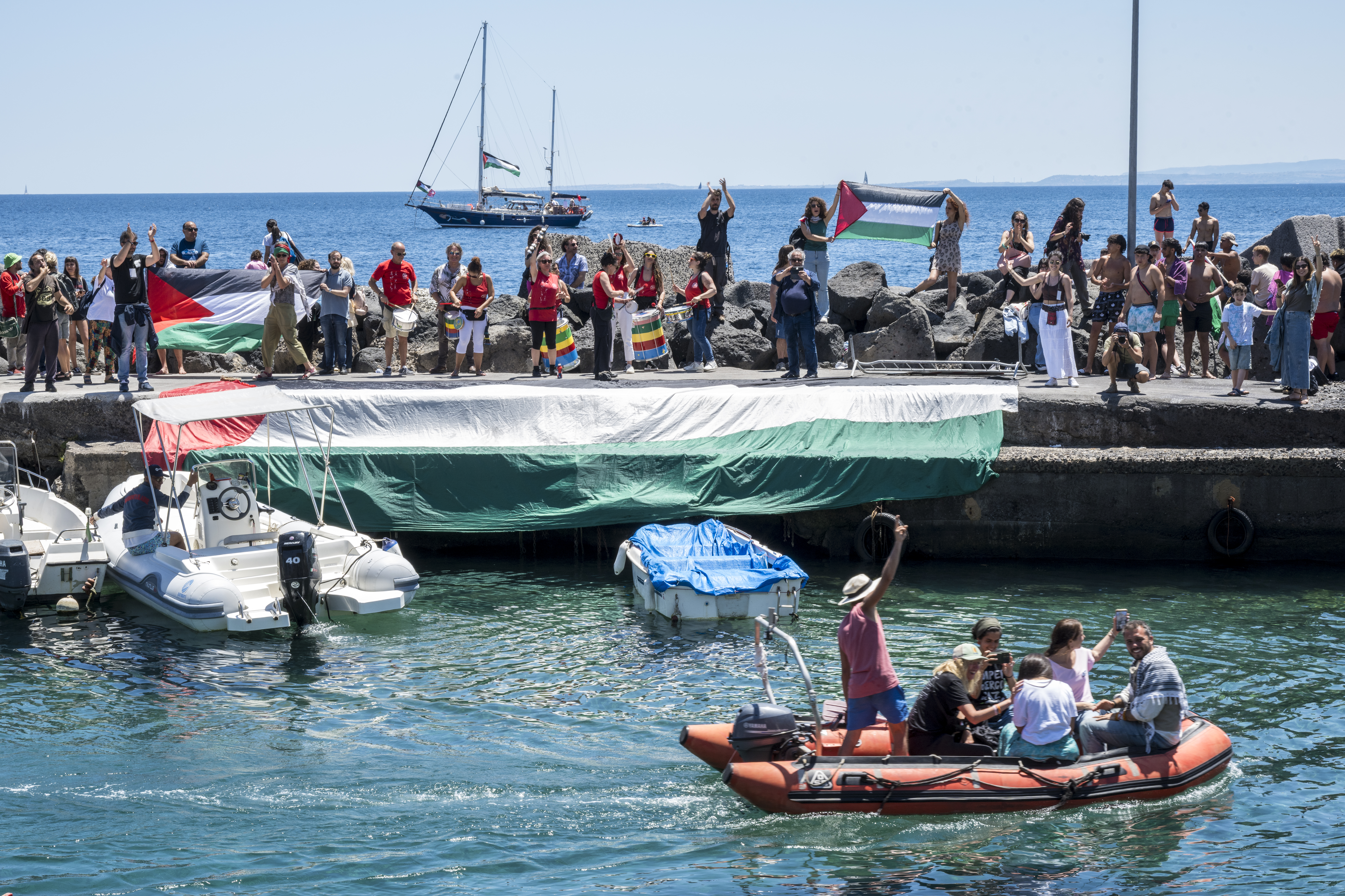 CATANIA, ITALY - JUNE 01: On board a dinghy, the activists of the Freedom Flotilla reach the ship Madleen to set sail for Gaza, while the crowd on the quay cheers and waves flags in solidarity on June 01, 2025 in Catania, Italy. Swedish activist Greta Thunberg is among those who will attempt to sail to Gaza on a boat organized by the Freedom Flotilla Coalition (FFC), in a bid to break Israel's blockade of the Palestinian territory. Freedom Flotilla had to abort a previous journey in early May after it said its boat came under attack by drones in international waters near Malta. (Photo by Fabrizio Villa/Getty Images)