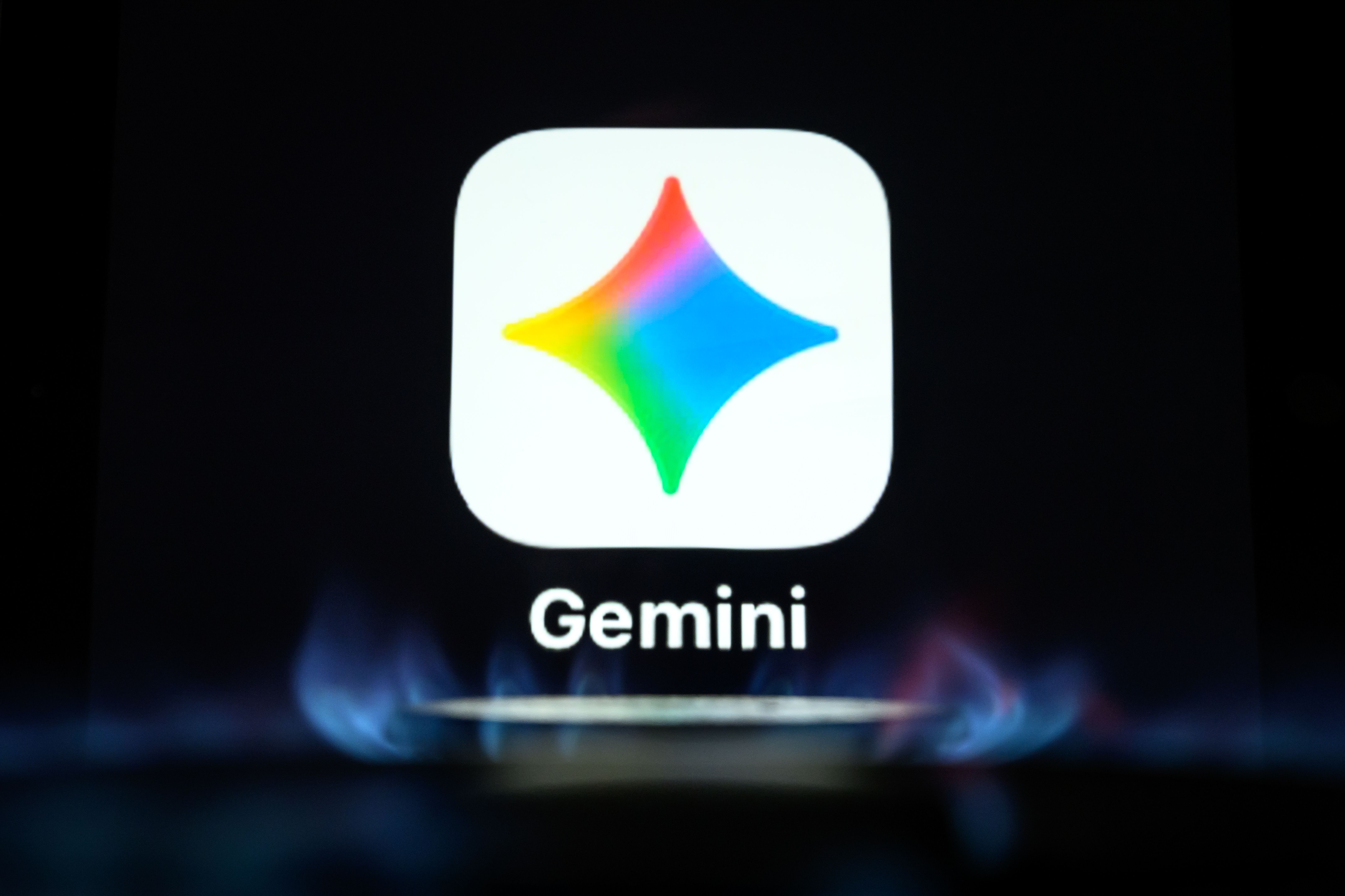 A screen showing the Gemini app icon, photographed through an orange flame.