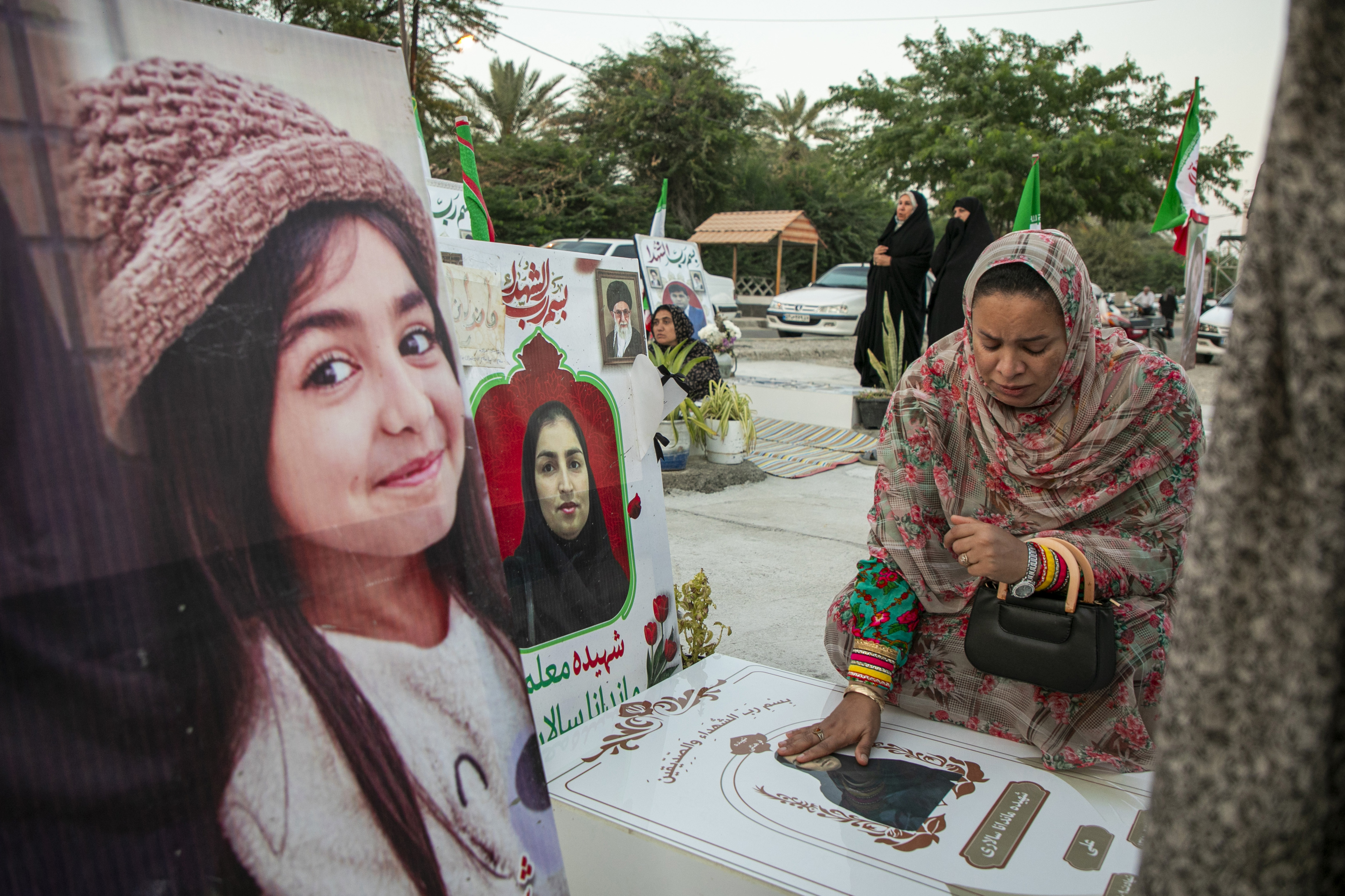 MINAB, IRAN - MAY 14: A woman touches the grave of a deceased relative, as people gather to mourn at the cemetery of Minab City on May 14, 2026 in Minab, Iran. On 28 February this year, a US military launched a missile strike that destroyed the all-girls Al-Shajara School in Minab, Iran, killing 175 people, including 47 schoolgirls and 26 teachers and causing global outrage. The attack is the deadliest civilian event of the 2026 Iran war. US investigators later stated American forces hit the school by mistake due to outdated intelligence, as the civilian school sat right next to an Iranian naval base. (Photo by Majid Saeedi/Getty Images)