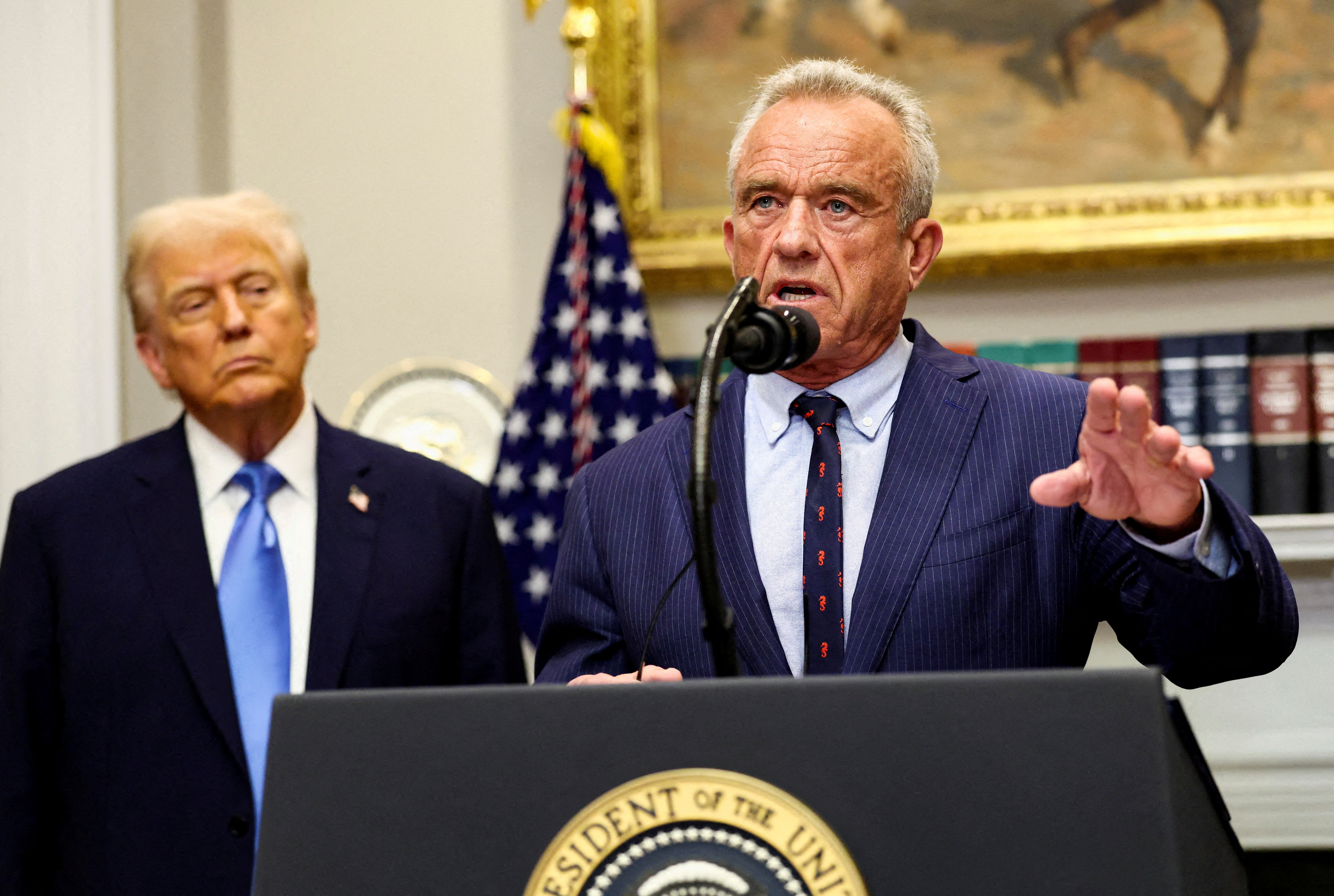 U.S. Secretary of Health and Human Services Robert F. Kennedy Jr. delivers remarks while U.S. President Donald Trump listens during a press conference to announce a link between autism and childhood vaccines and the use of popular pain medication Tylenol for pregnant women and children, claims which are not backed by decades of science, at the White House. [Kevin Lamarque/Reuters]