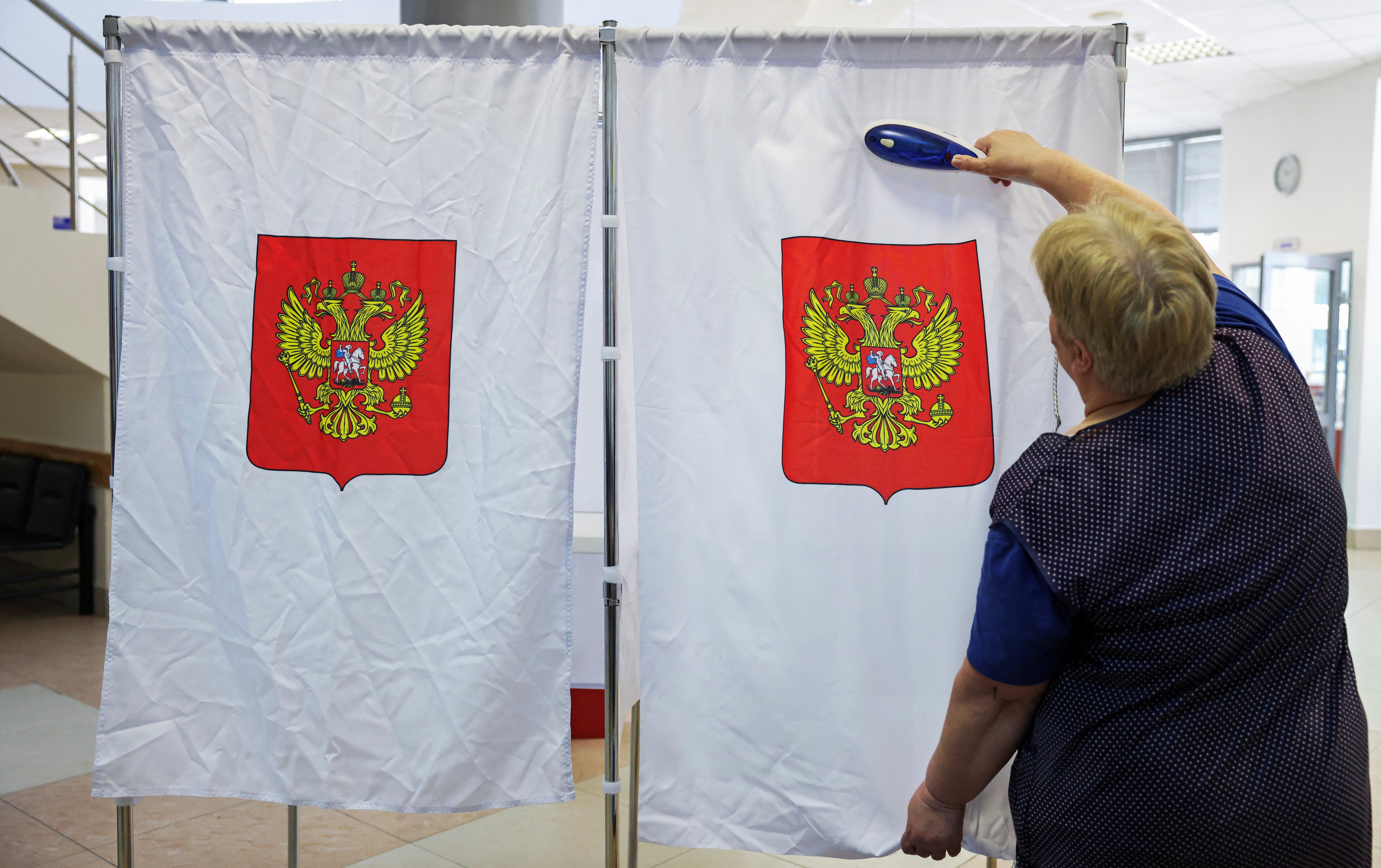 A worker steams a curtain in a voting booth at a polling station ahead of the parliamentary elections in Podolsk, Moscow region, Russia, September 17, 2026. REUTERS/Ramil Sitdikov